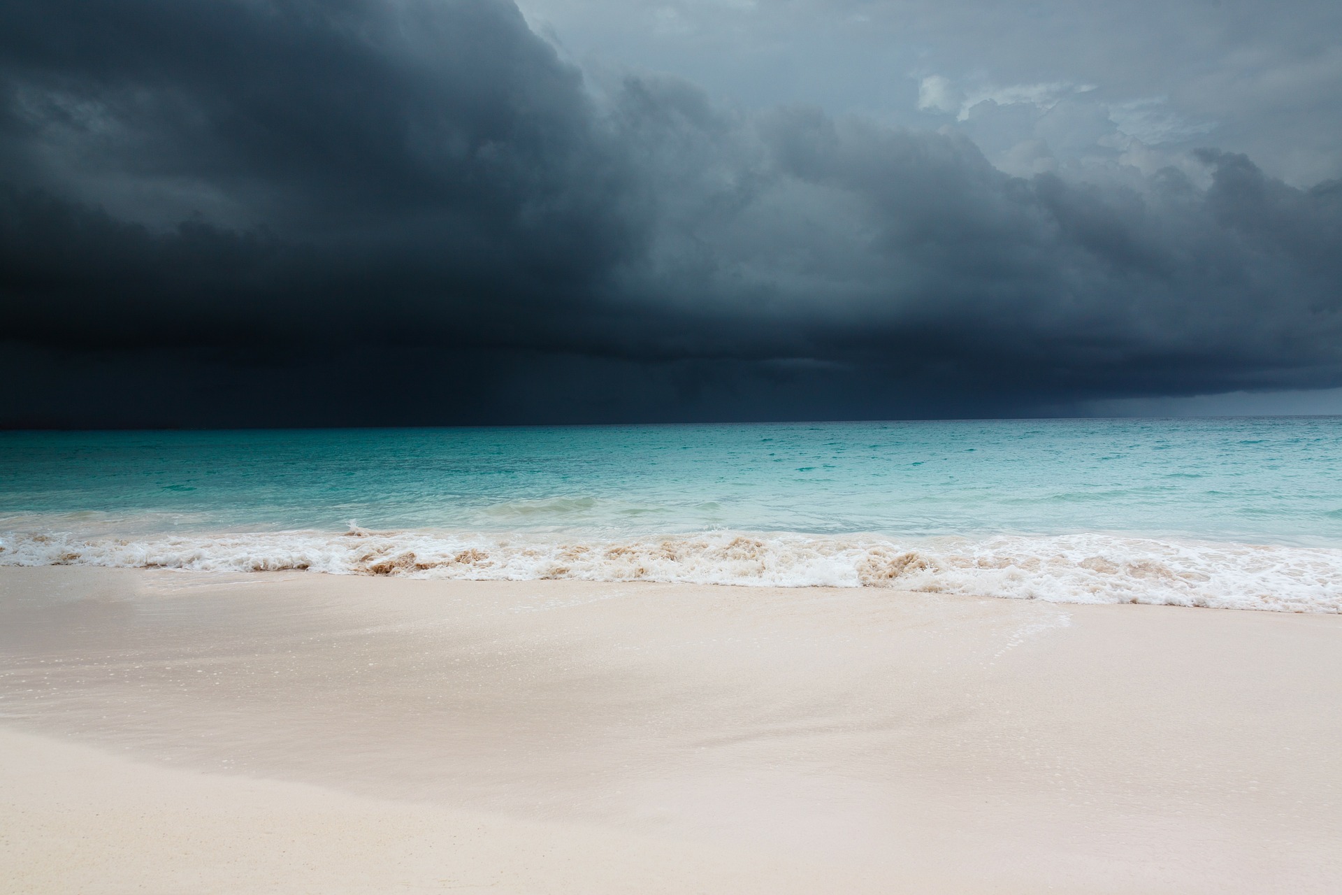 Beach turquoise sea with dark clouds on horizon